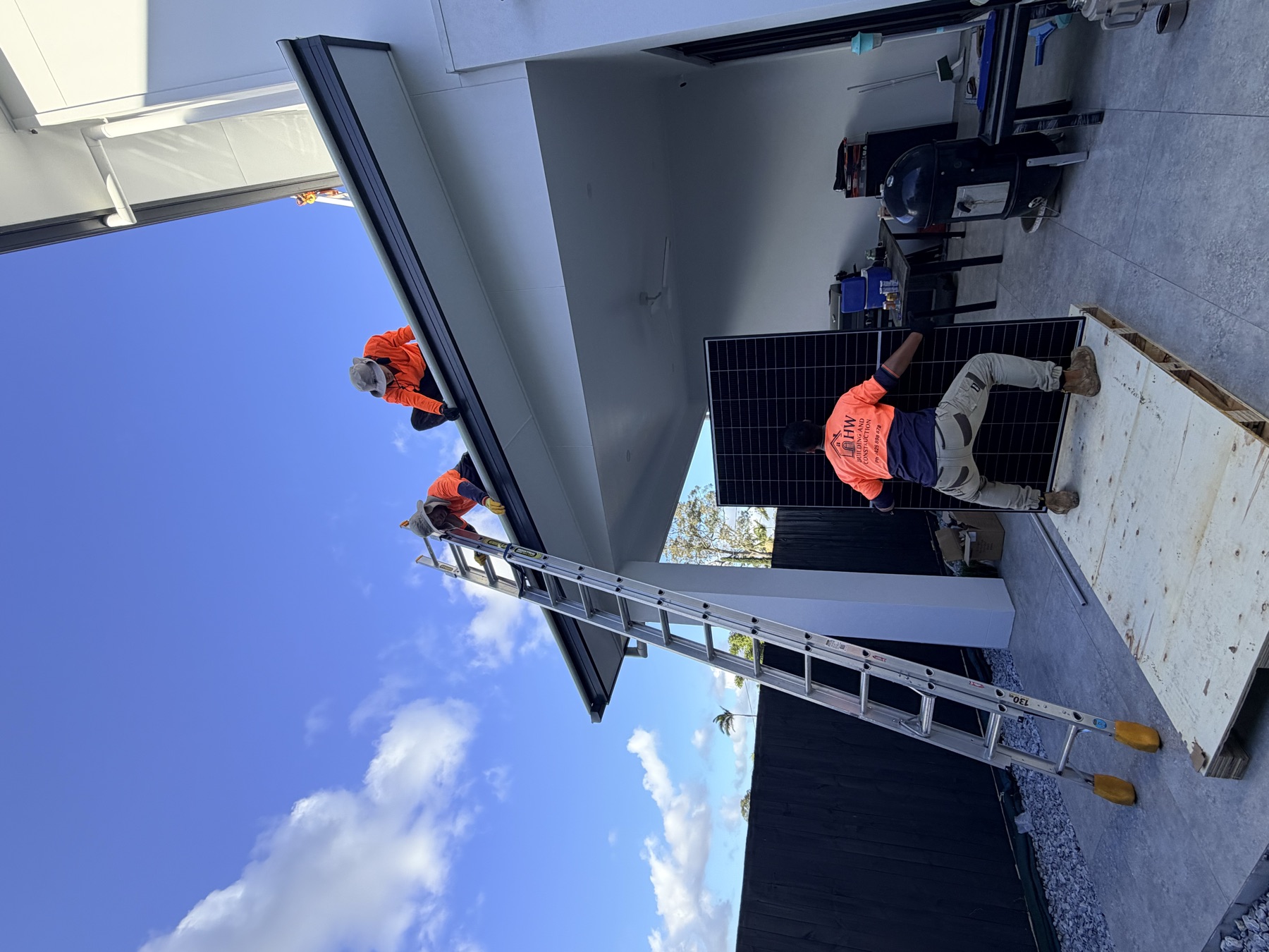 Crew carrying a solar panel up to the roof